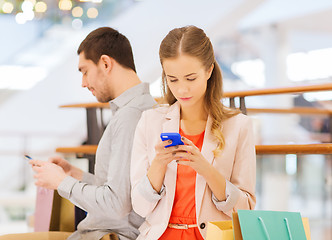 Image showing couple with smartphones and shopping bags in mall