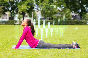 Image showing smiling woman stretching back on mat outdoors