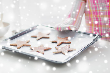 Image showing close up of woman with cookies on oven tray