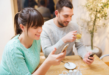Image showing smiling couple with smartphones drinking tea