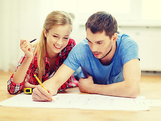 Image showing smiling couple looking at blueprint at home