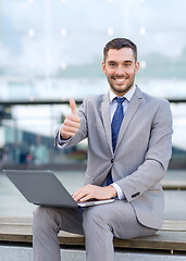 Image showing smiling businessman working with laptop outdoors