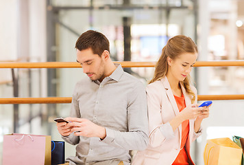 Image showing couple with smartphones and shopping bags in mall