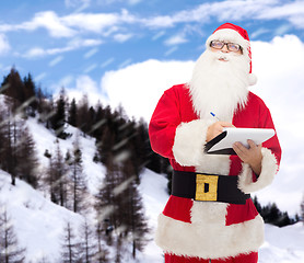 Image showing man in costume of santa claus with notepad