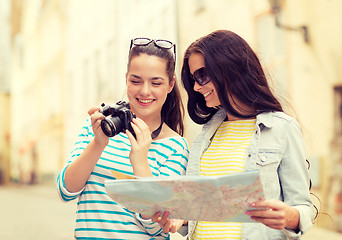 Image showing smiling teenage girls with map and camera