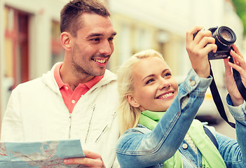 Image showing smiling couple with map and photocamera in city