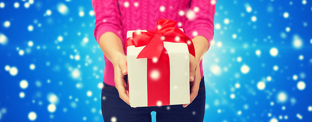 Image showing close up of woman in pink sweater holding gift box