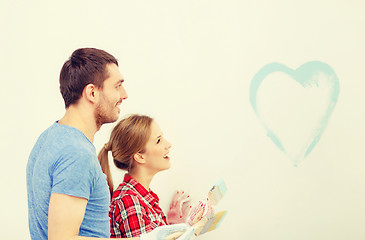 Image showing smiling couple painting small heart on wall