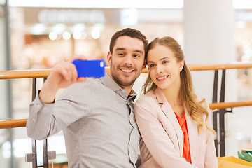 Image showing happy couple with smartphone taking selfie in mall