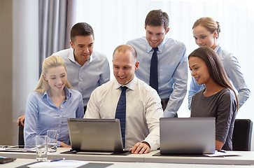 Image showing smiling businesspeople with laptops in office