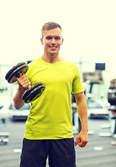 Image showing smiling man with dumbbell in gym