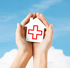 Image showing hands holding paper house with red cross