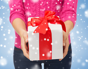 Image showing close up of woman in pink sweater holding gift box