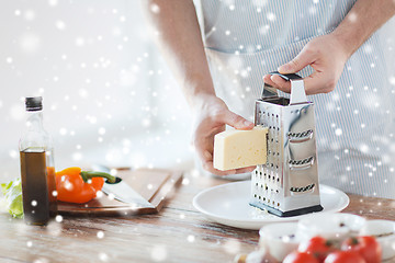 Image showing close up of male hands with grater grating cheese