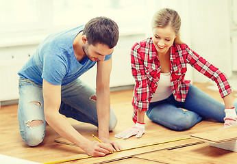 Image showing smiling couple measuring wood flooring