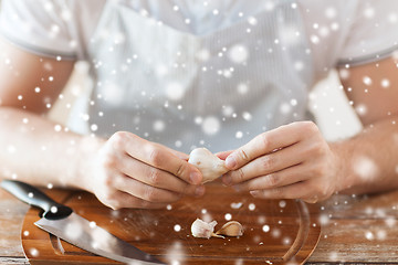 Image showing close up of male hands taking off garlic peel