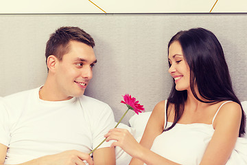 Image showing smiling couple in bed with flower