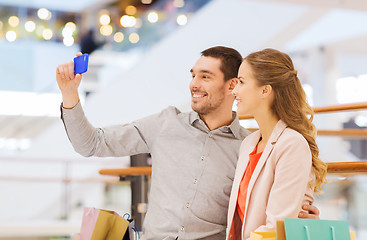 Image showing happy couple with smartphone taking selfie in mall