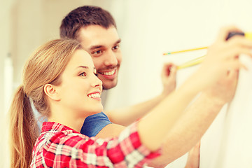 Image showing smiling couple measuring wall