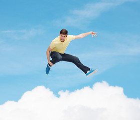 Image showing smiling young man jumping in air