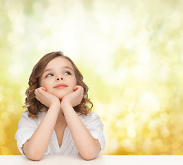 Image showing beautiful girl sitting at table and looking up