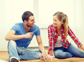 Image showing smiling couple measuring wood flooring