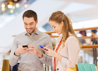 Image showing couple with smartphones and shopping bags in mall