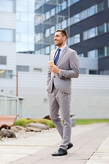 Image showing young serious businessman with paper cup outdoors