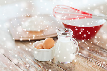 Image showing close up of milk jug, eggs, whisk and flour