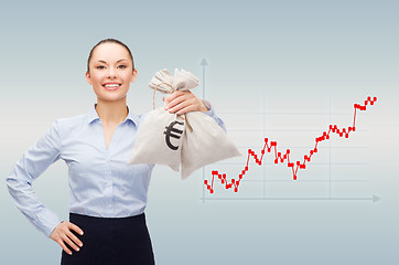 Image showing happy businesswoman holding money bags with dollar