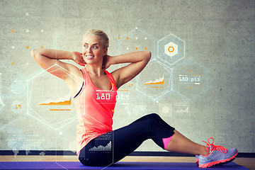 Image showing smiling woman doing exercises on mat in gym
