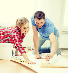 Image showing smiling couple smearing wallpaper with glue