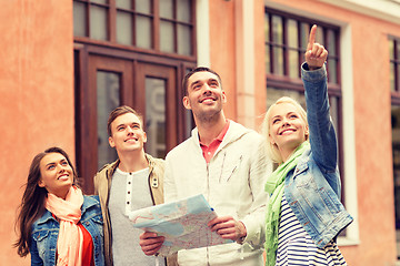Image showing group of smiling friends with map exploring city