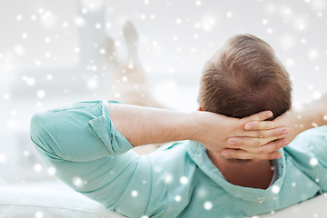 Image showing man lying or sitting on sofa at home from back