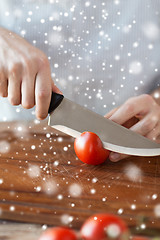 Image showing close up of man cutting tomato on board with knife