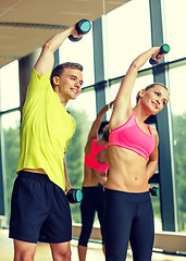 Image showing smiling man and woman with dumbbells in gym