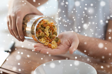 Image showing close up of man emptying jar with colorful pasta