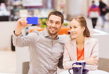 Image showing happy couple with smartphone taking selfie in mall