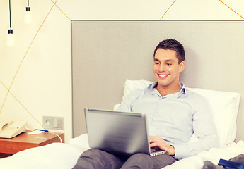 Image showing happy businesswoman with laptop in hotel room