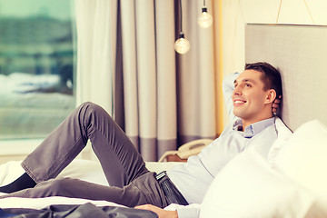 Image showing happy businesswoman lying in bed in hotel room