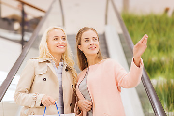 Image showing young women pointing finger on escalator in mall