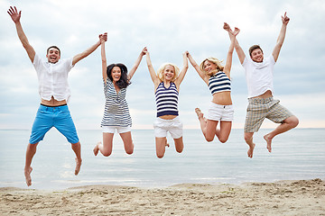 Image showing smiling friends in sunglasses walking on beach