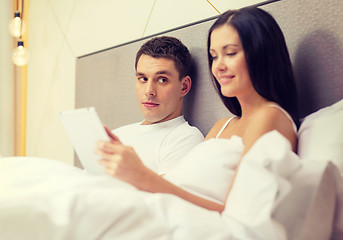 Image showing smiling couple in bed with tablet pc computers