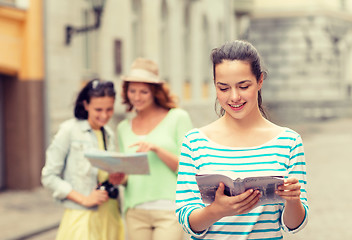 Image showing smiling teenage girls with city guides and camera