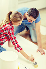 Image showing smiling couple smearing wallpaper with glue