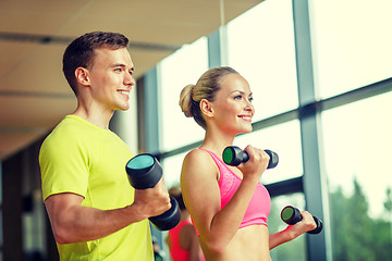 Image showing smiling man and woman with dumbbells in gym