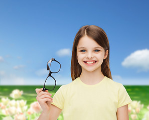Image showing smiling cute little girl holding black eyeglasses