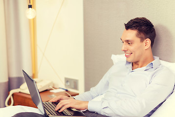 Image showing happy businesswoman with laptop in hotel room