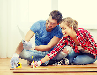 Image showing smiling couple measuring wood flooring