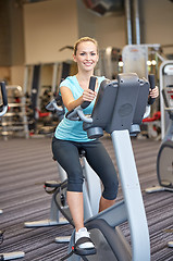 Image showing smiling woman exercising on exercise bike in gym